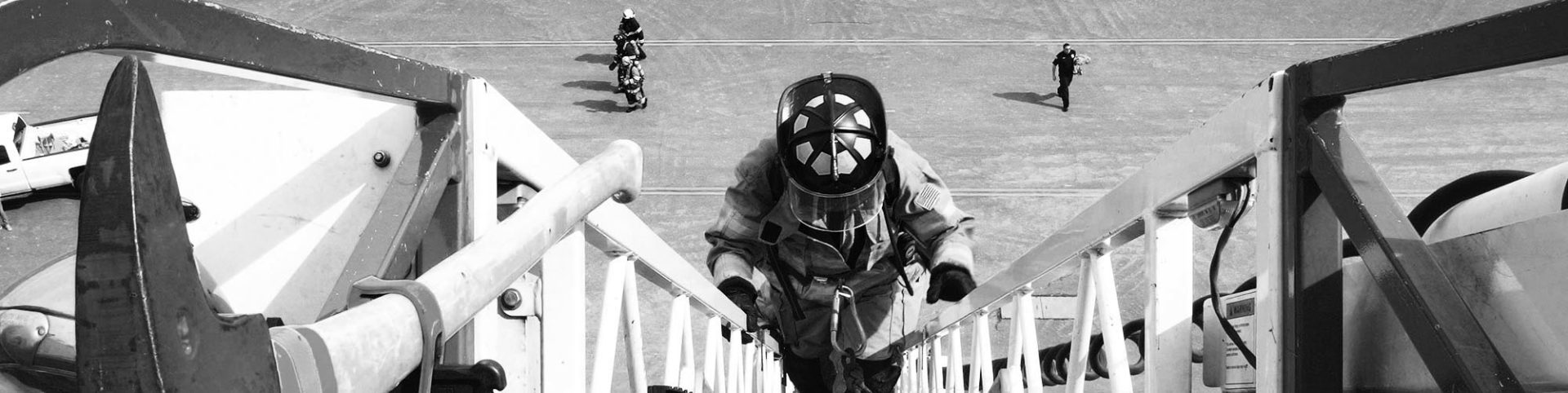 Firefighter climbs ladder with helmet and mask on